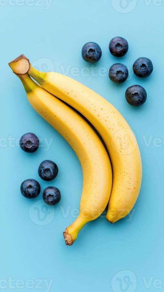 Fresh bananas and blueberries creatively arranged on a vibrant blue background. photo