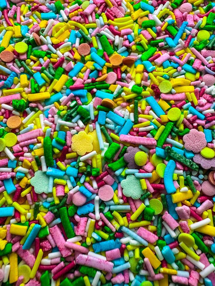Multicolored small candies of different shapes. Top view. Bright vertical background photo