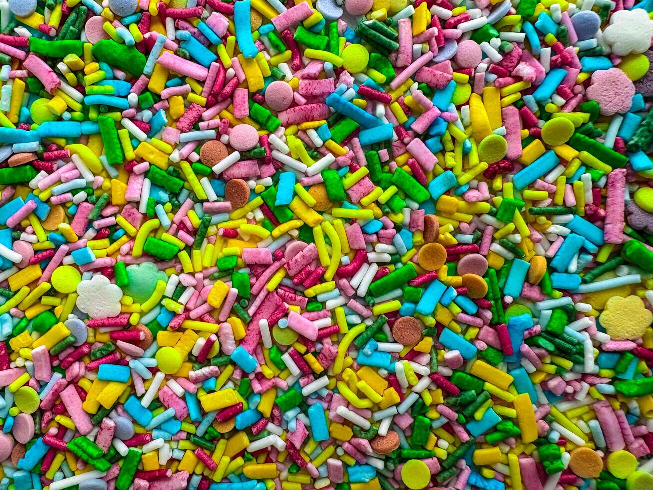 Multicolored small candies of different shapes. Top view. Bright horizontal background photo