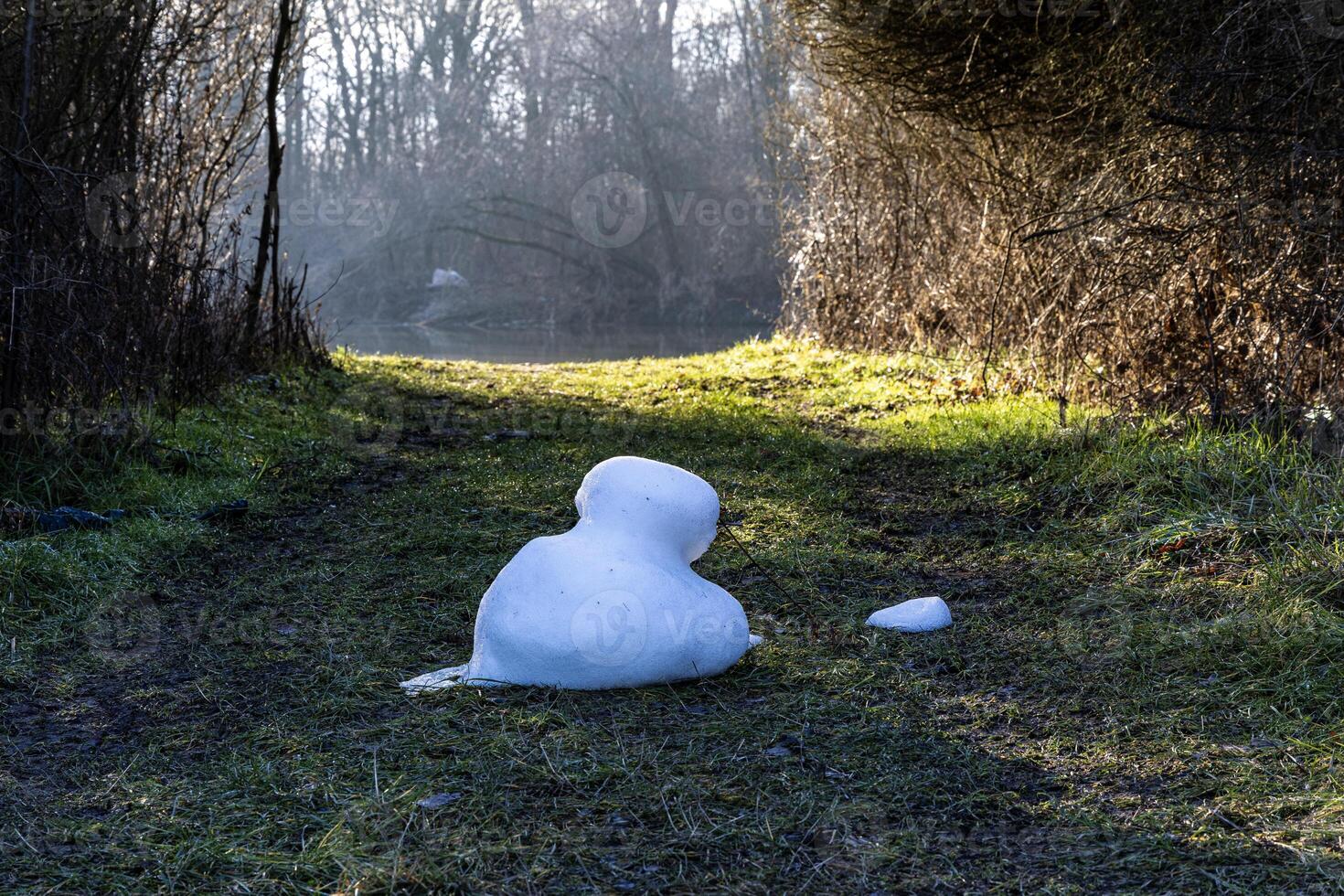 A melted snowman in spring on a meadow by the river. Poland photo