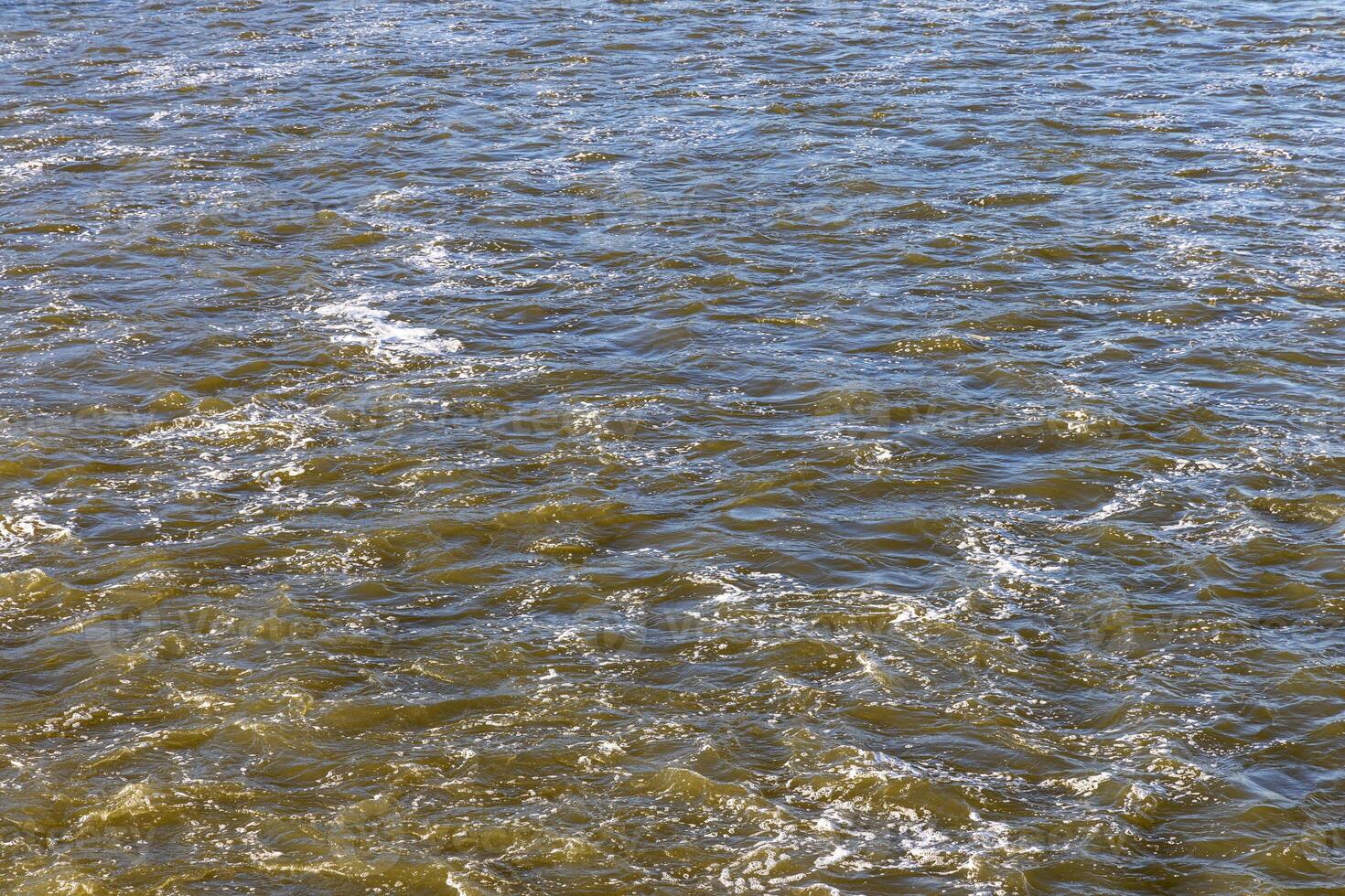 Rough flow of foaming water in the river, close-up, background. photo