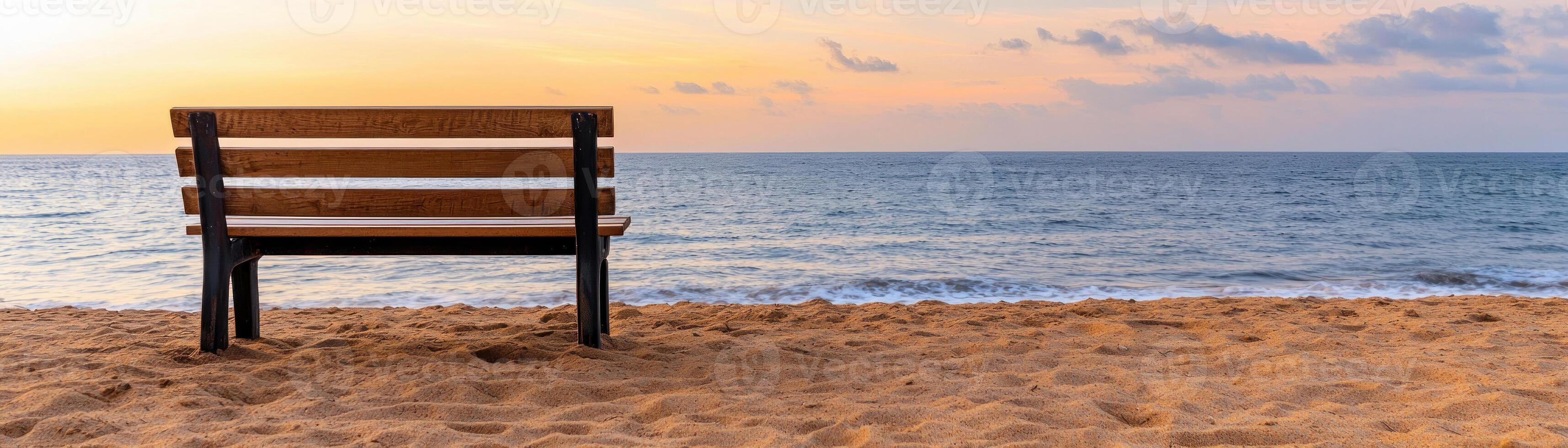 A serene beach view with a wooden bench overlooking the tranquil ocean at sunset. photo