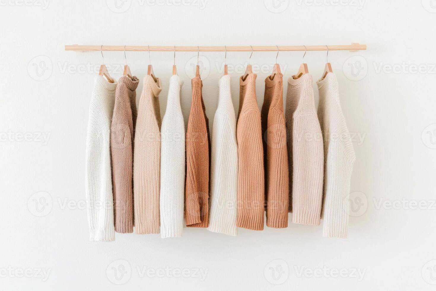Elegant collection of soft, neutral-colored sweaters hanging on a minimalist rack. photo