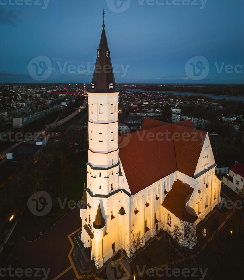 Siauliai, Lithuania, 2024 - aerial fly over view illuminated Roman catholic Church of Saints Peter and Paul. Siauliai city landmarks and sightseeing attractions photo