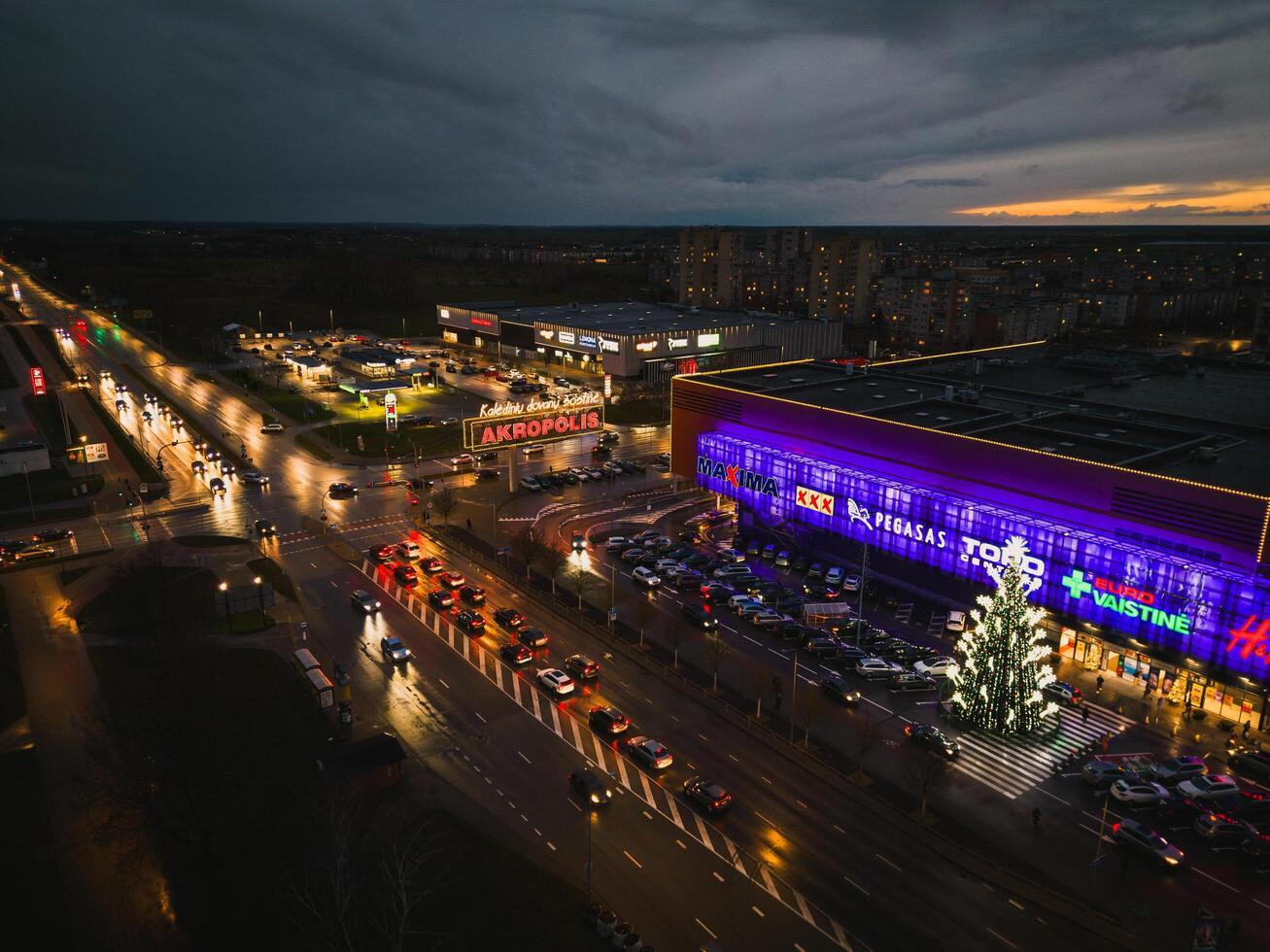 Siauliai, Lithuania, 2024- Popular lithuanian shopping mall Akropolis with Illuminated Xmas tree and customers go shopping. Black friday winter celebrations shopping boom photo