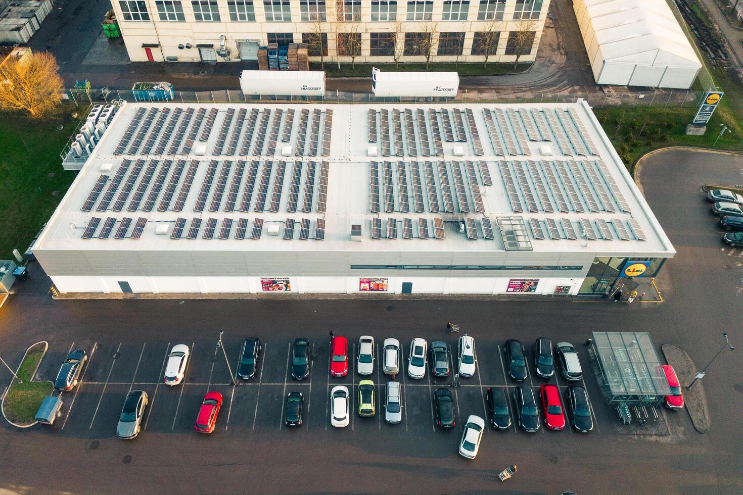 Siauliai, Lithuania, 2024- Aerial top down cars in parking and customers go do shopping to german Lidl supermarket building with solar panels on rooftop.Sustainability business concept photo