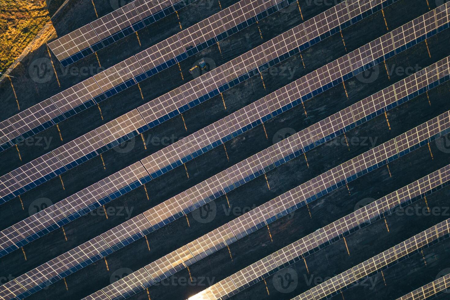 Top down revealing rising view man worker working at solar power station drive tractor in row of solar panels. A worker on a garden tractor mows grass on solar panel farm in Lithuania, Europe union. photo