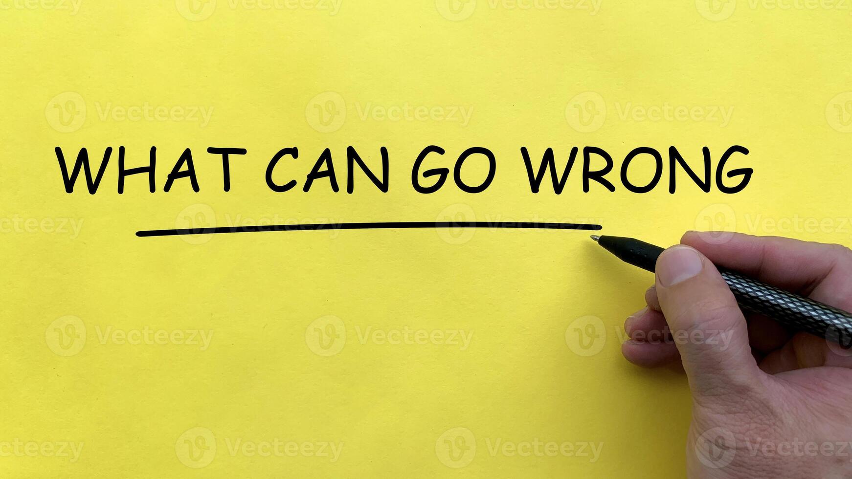 Hand writing What Can Go Wrong text on yellow cover board photo