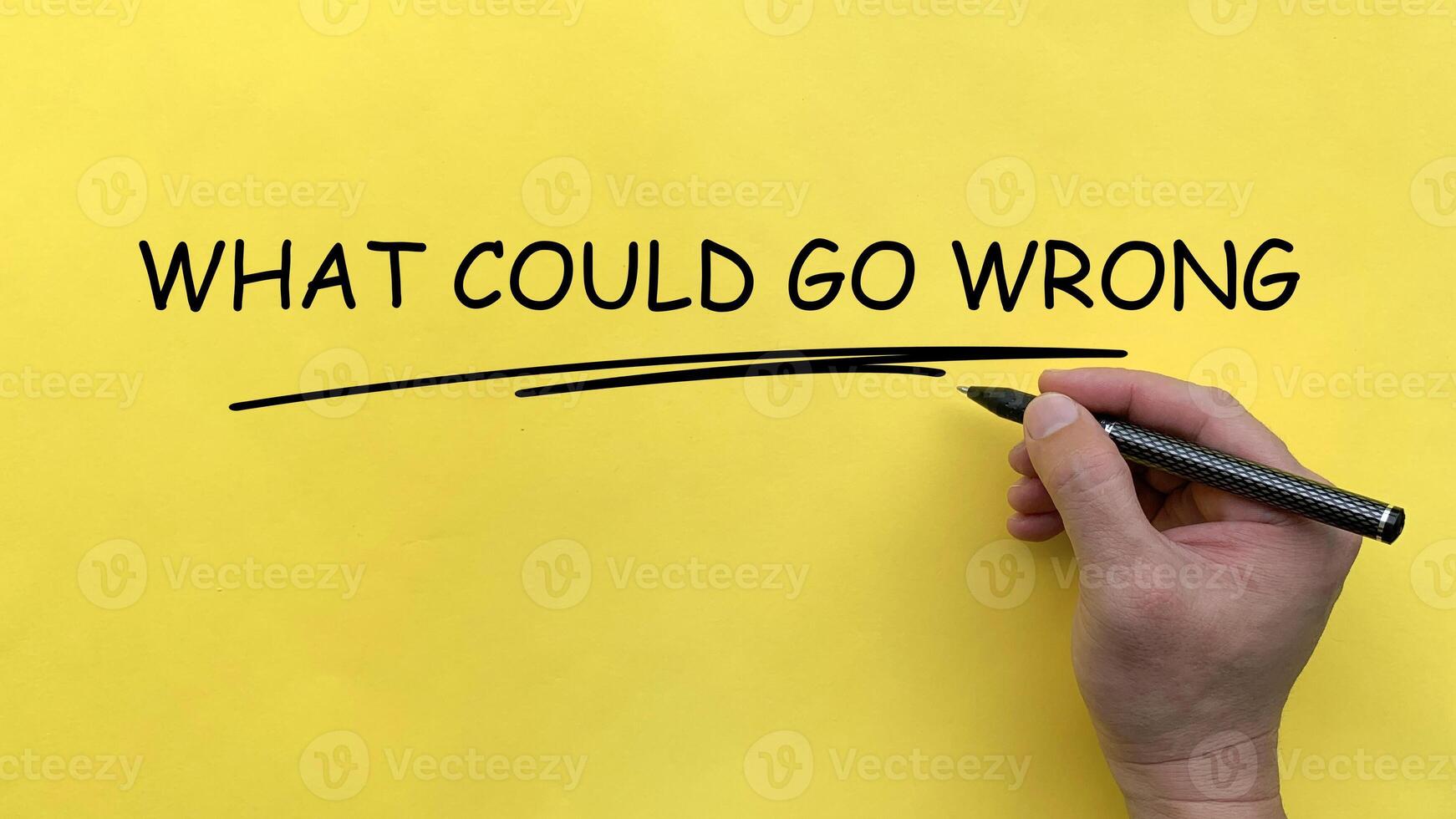 Hand writing What Could Go Wrong text on yellow cover board photo