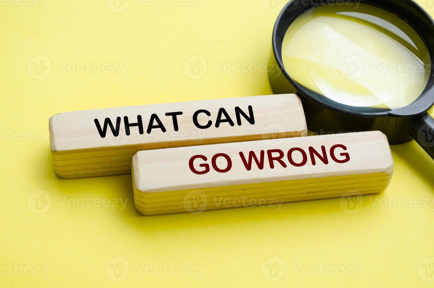 Side view of What Can Go Wrong text on wooden blocks with magnifying glass photo