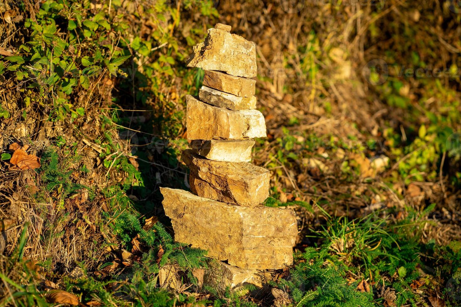 Small stone pyramid on a background of stone and green ivy photo