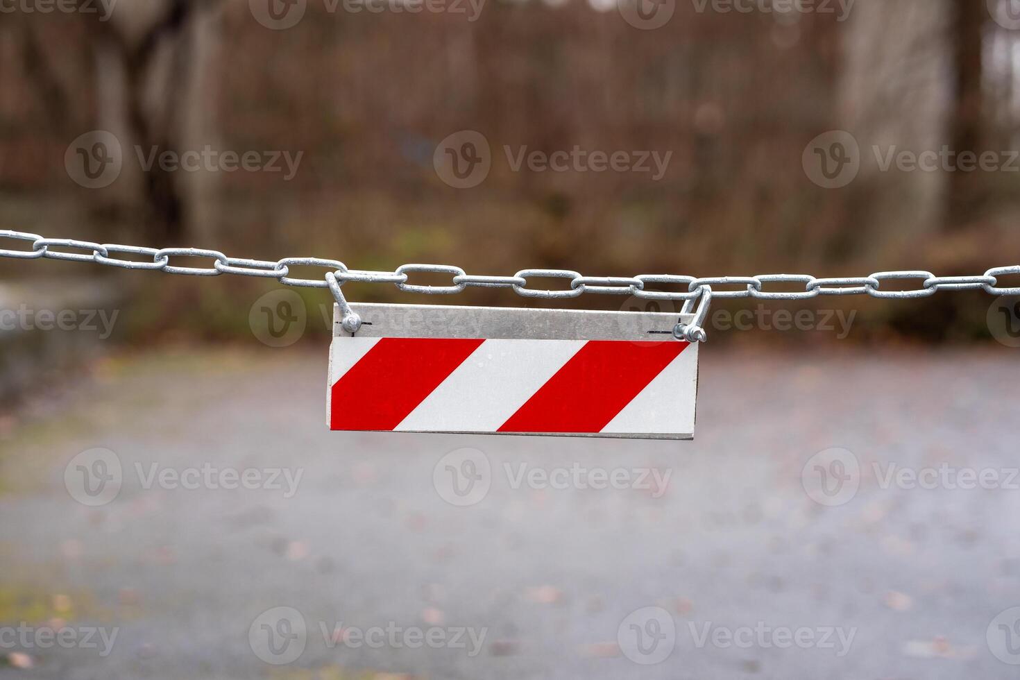 View of a red and white diagonal striped sign hanging on a chain photo