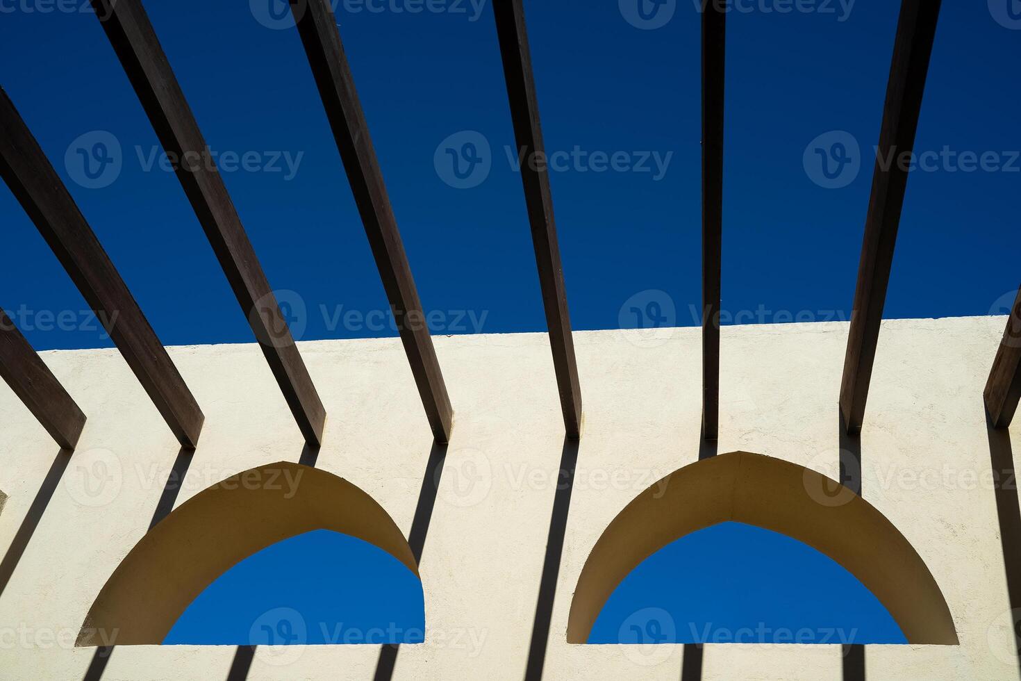 two Arabic windows on a yellow wall with crossbars instead of a roof photo