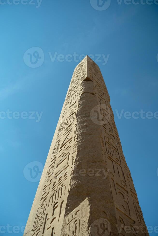 Ancient Egyptian obelisk close-up against sky background photo