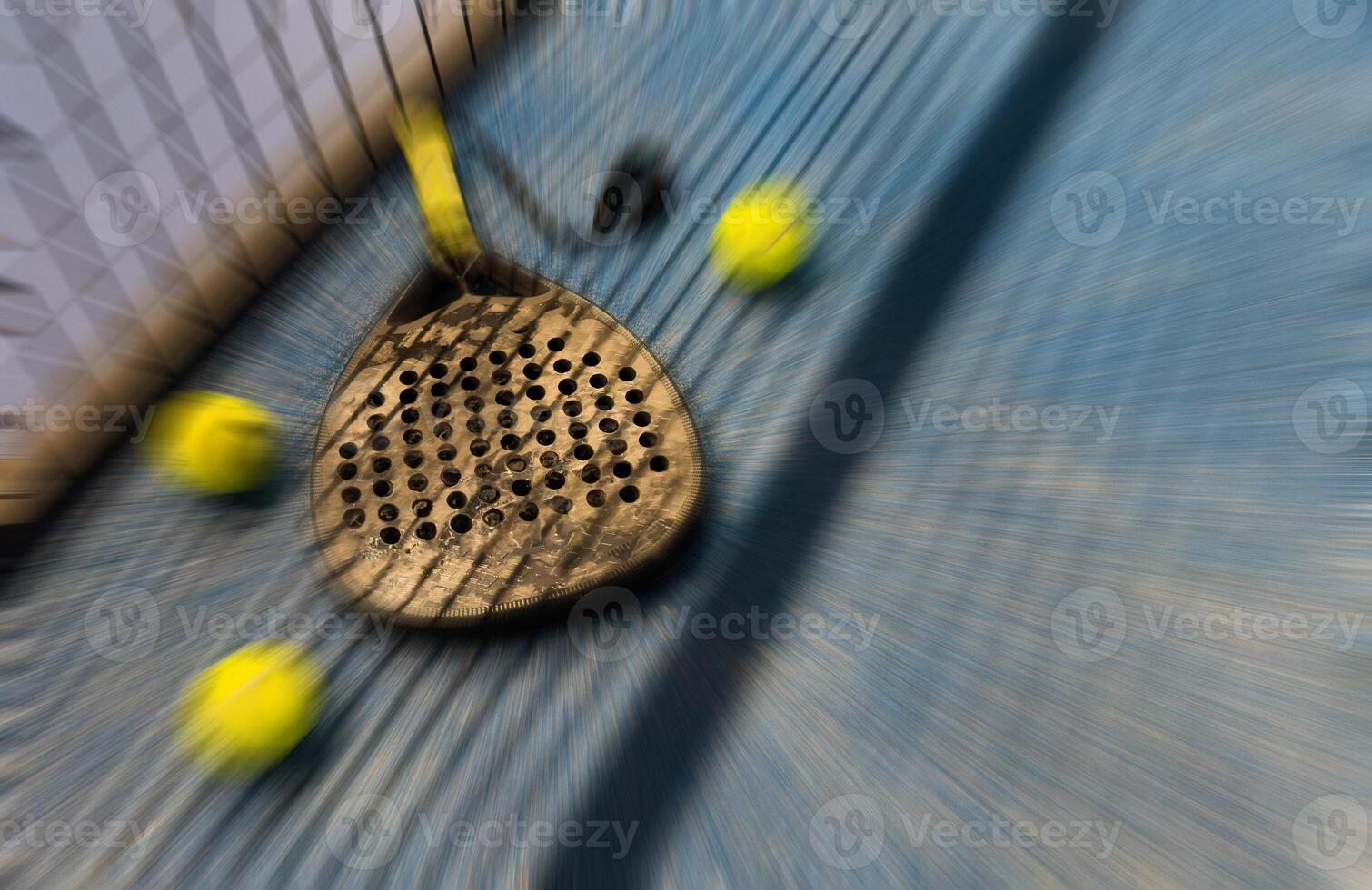 A padel or paddle tennis racket and a bright yellow tennis ball lie on a blue court. photo