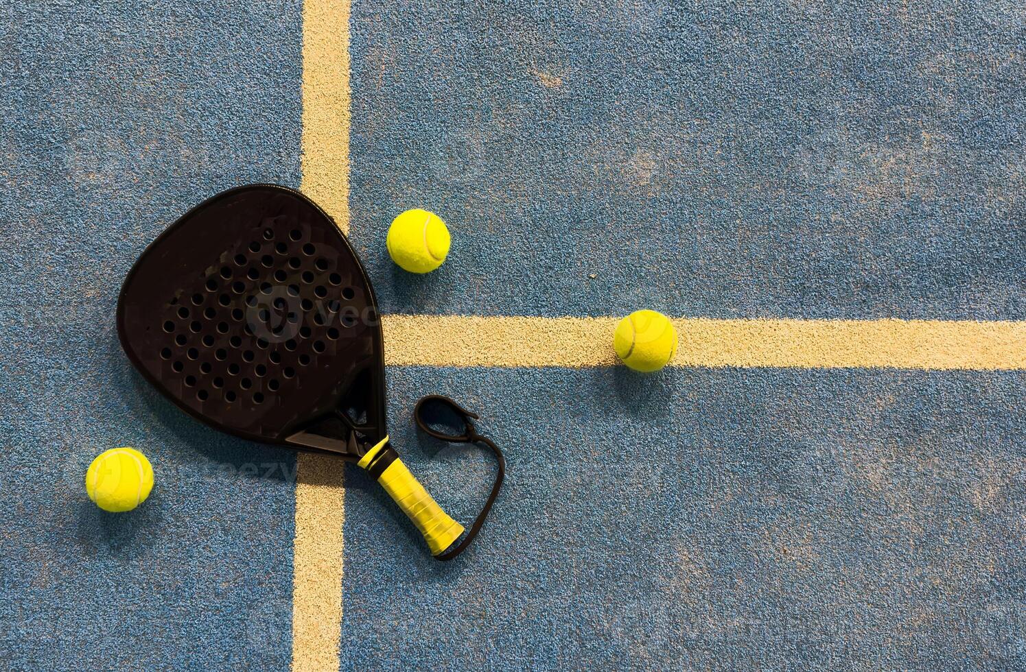 padel racket and yellow balls placed on court near net photo