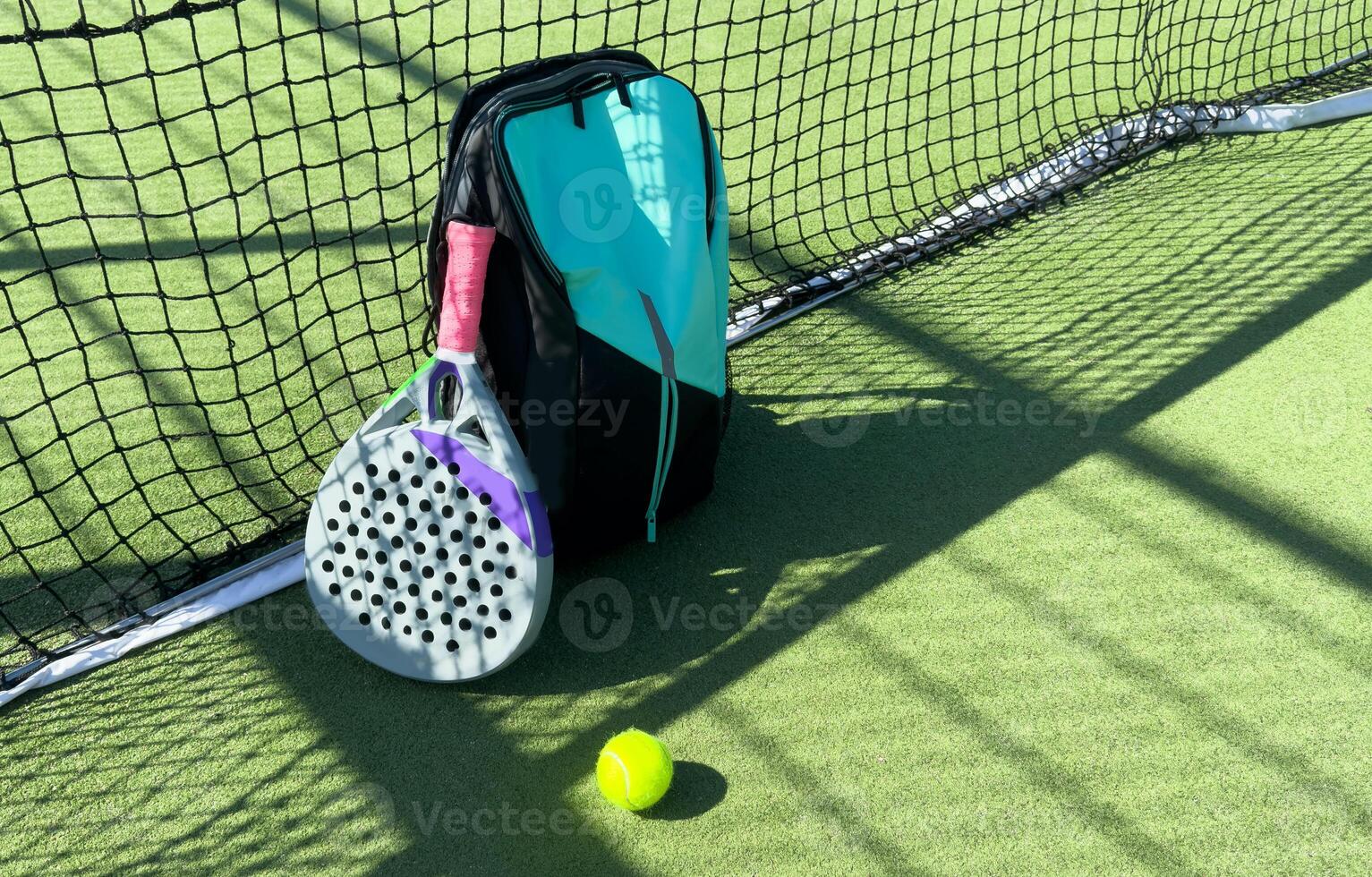 Blue bag with tennis padel racket and ball on grassy field at tennis court, copy space. Unaltered, sport, competition, green, nature and summer concept. photo