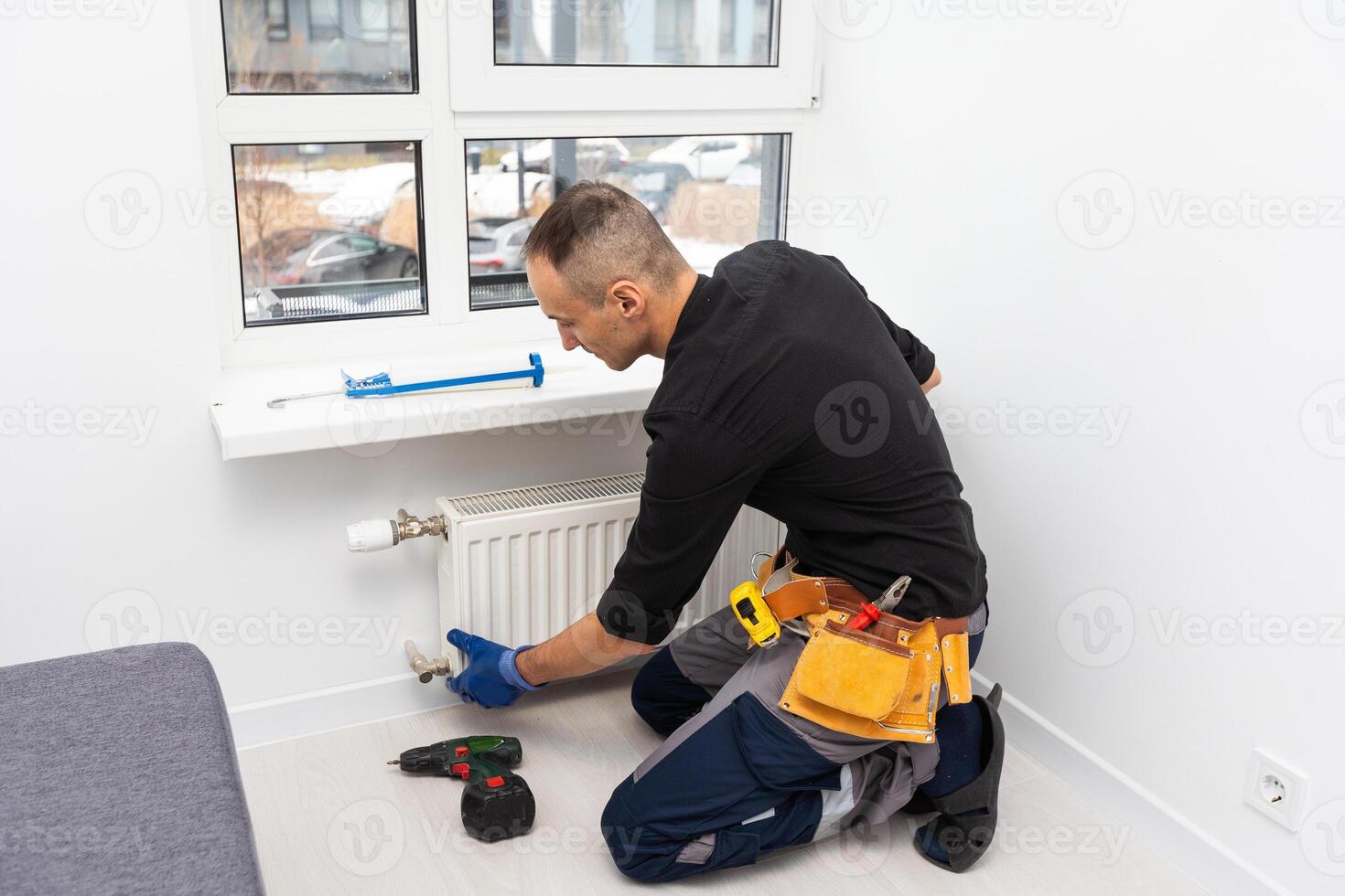 Professional plumbers installing new heating radiator in room photo