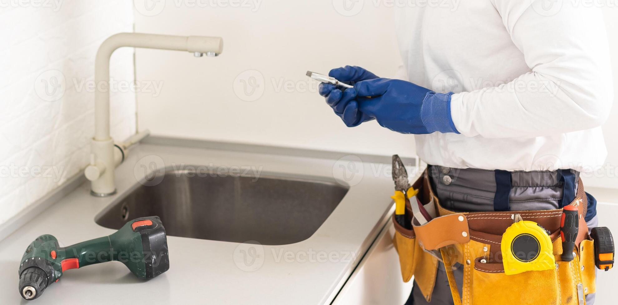 Male Plumber In Overall Fixing Sink photo