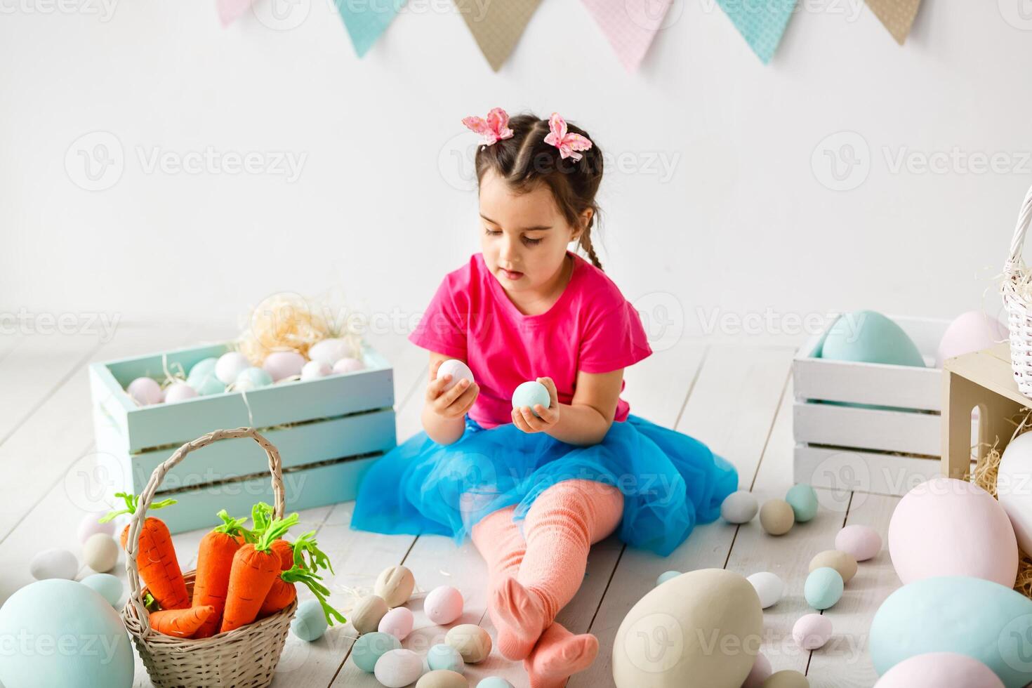 Happy Easter Cute little child girl wearing bunny ears on Easter day. Girl sitting with a basket of Easter eggs. Child girl laughs and enjoys spring and a holiday. photo