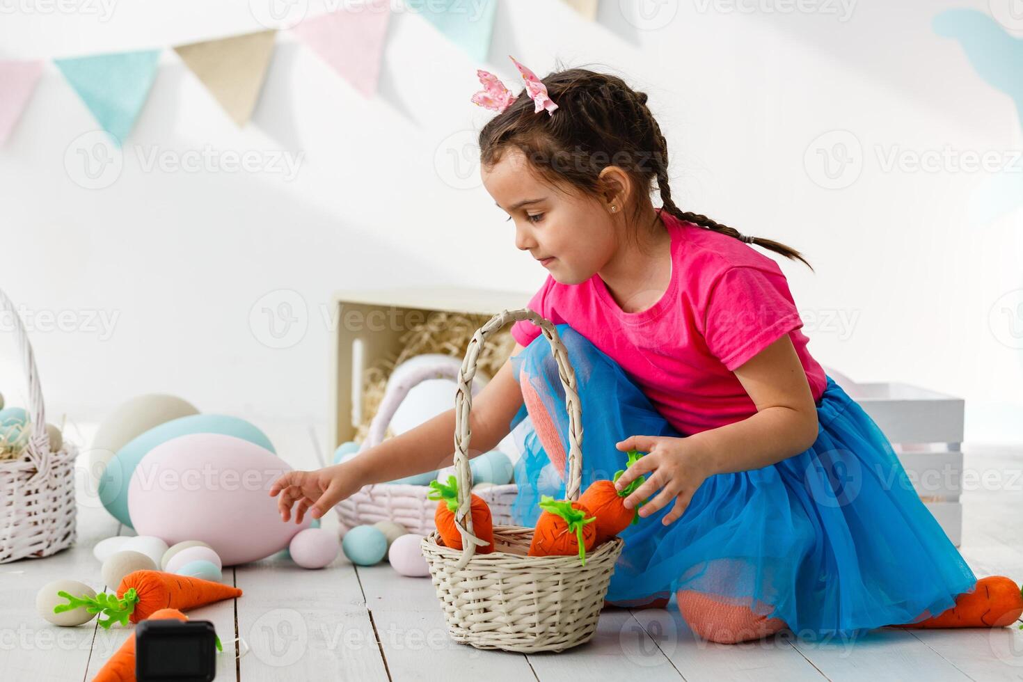 Getting ready to Easter. Lovely little girl holding an Easter egg and smiling with decoration in the background photo