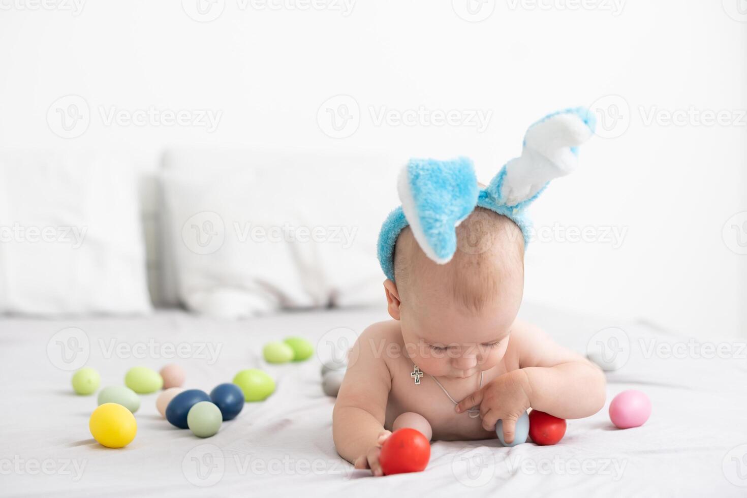 Portrait of a cute baby dressed in Easter bunny ears with a basket full of eggs photo
