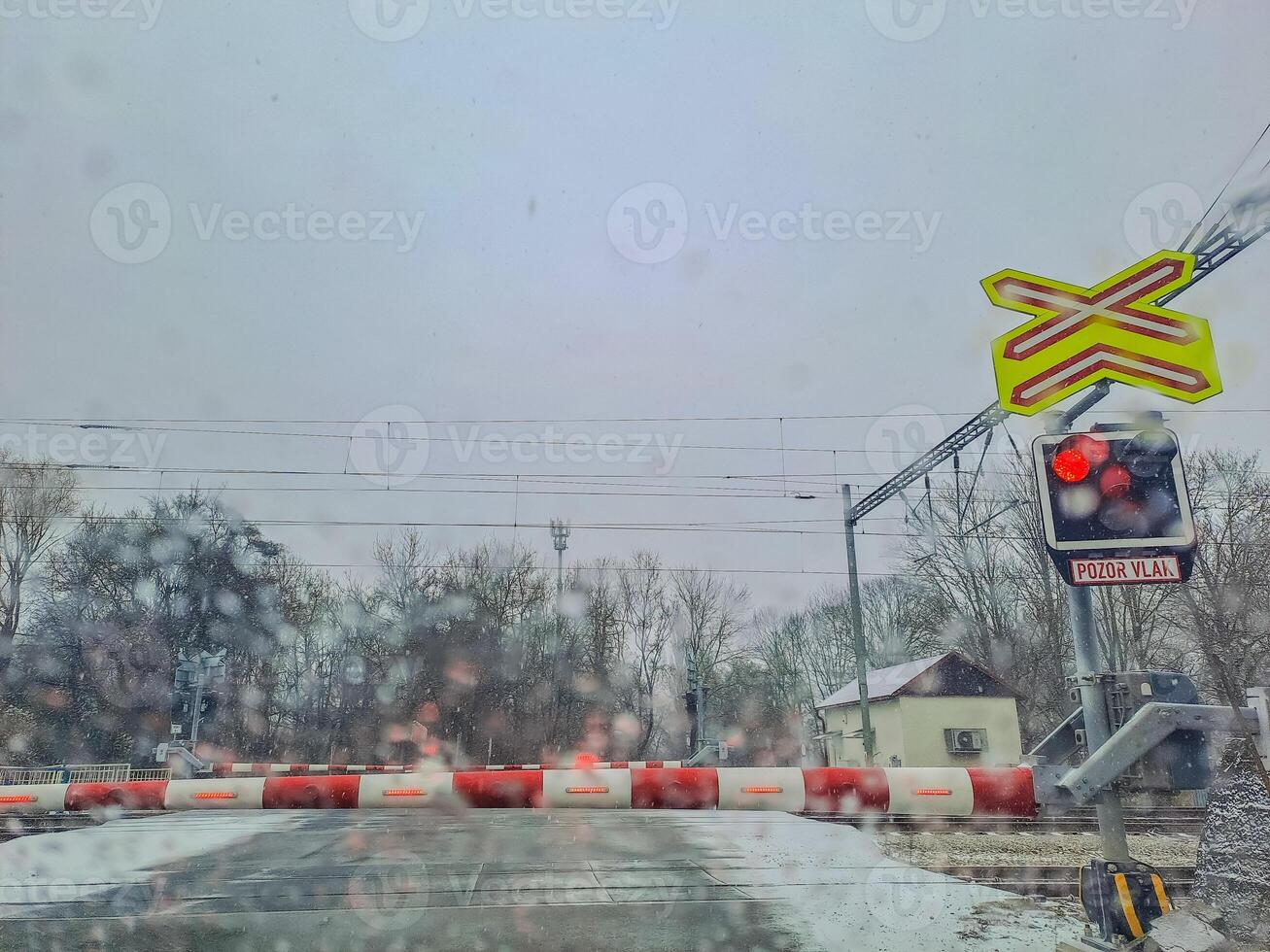 Snow-covered railroad crossing on the road in a winter, closed barriers down photo