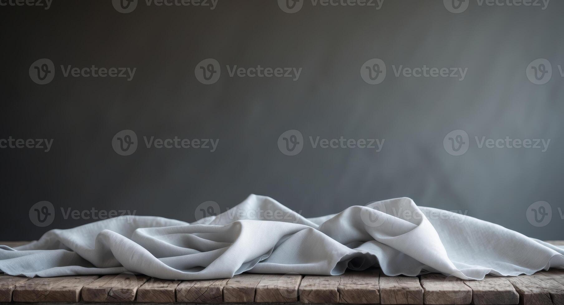 Gray Fabric Draped on Rustic Wooden Table with Dark BackgroundGray Fabric Draped on Rustic Wooden Table with Dark Background. photo