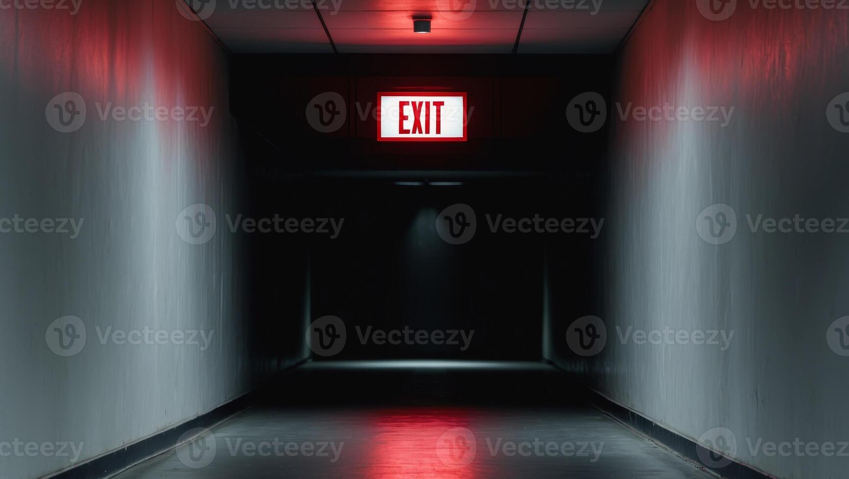 Dark hallway with illuminated exit sign casting red glow photo