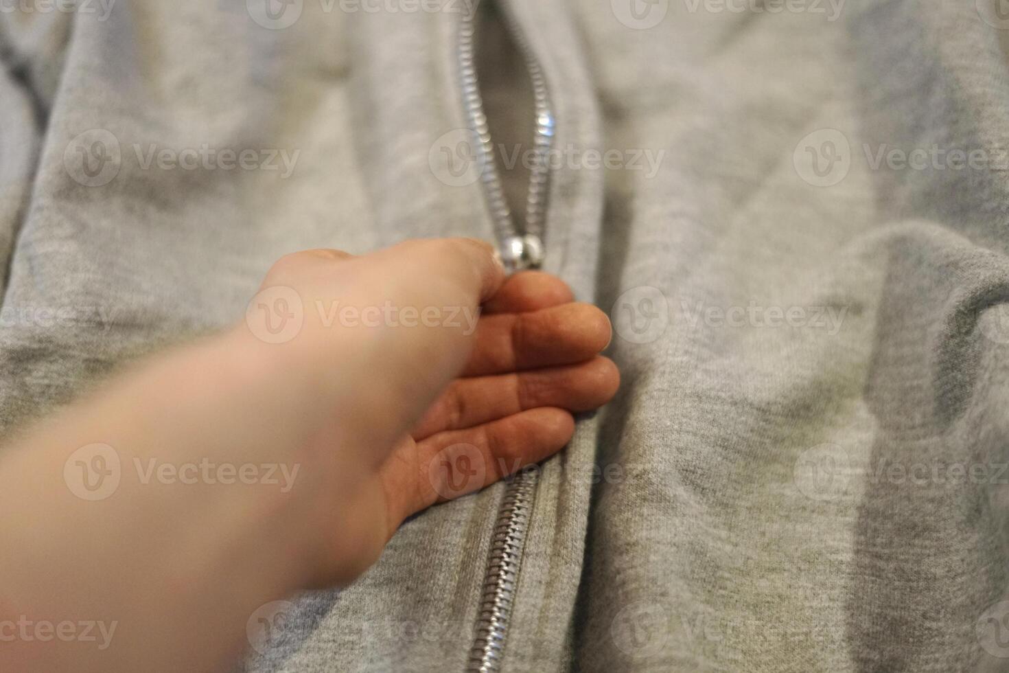 woman hand unzipping grey jacket with silver zip lock winter cold warm clothes open close photo