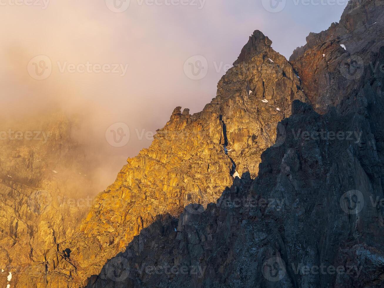 Scenic landscape with golden light in mountain top in low clouds in yellow sunrise colors. photo