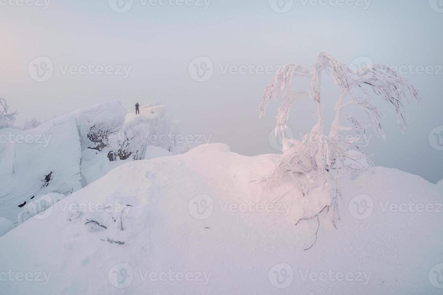 man stands on top of a snowy mountain photo
