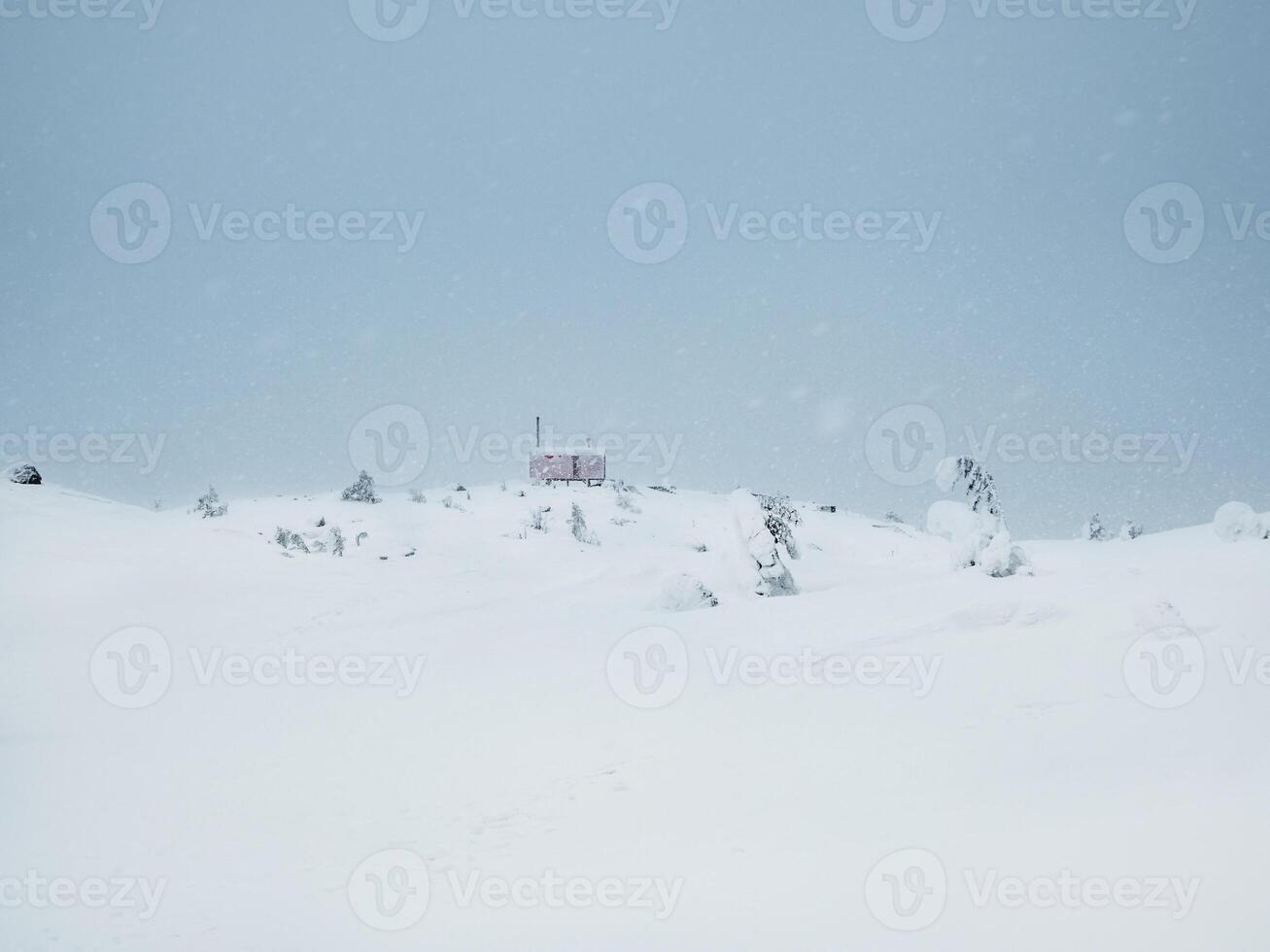 Soft focus. Poor visibility. Lonely house in a snowfall on a foggy snow-covered mountain. Winter holidays, extreme adventures in winter. photo