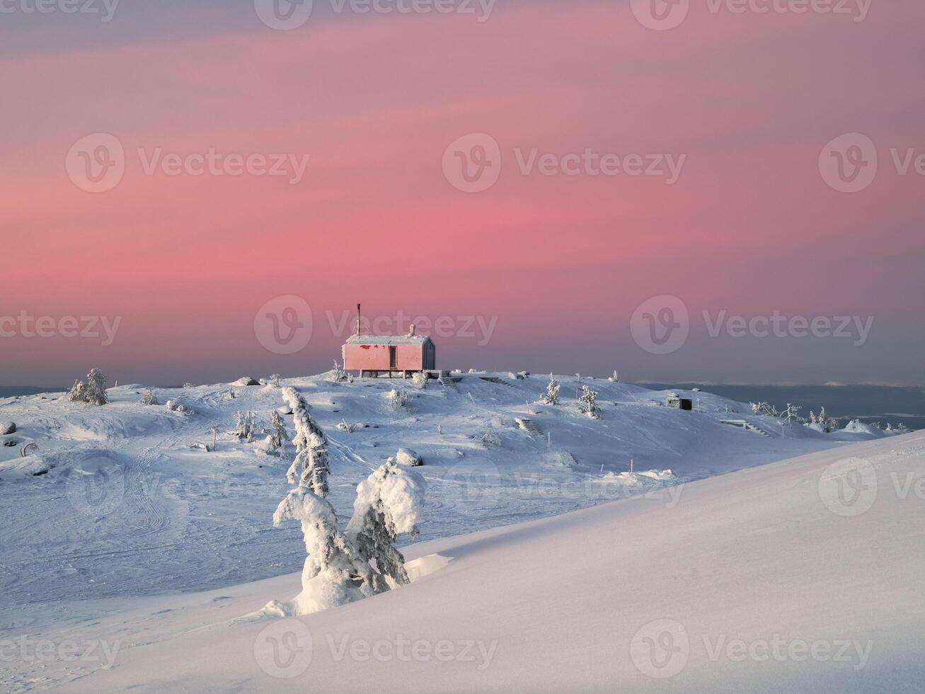 Cozy northern guest house on a snowy hill at dawn. Cabin in winter dawn. Lonely house on a hilltop in the cool morning. photo