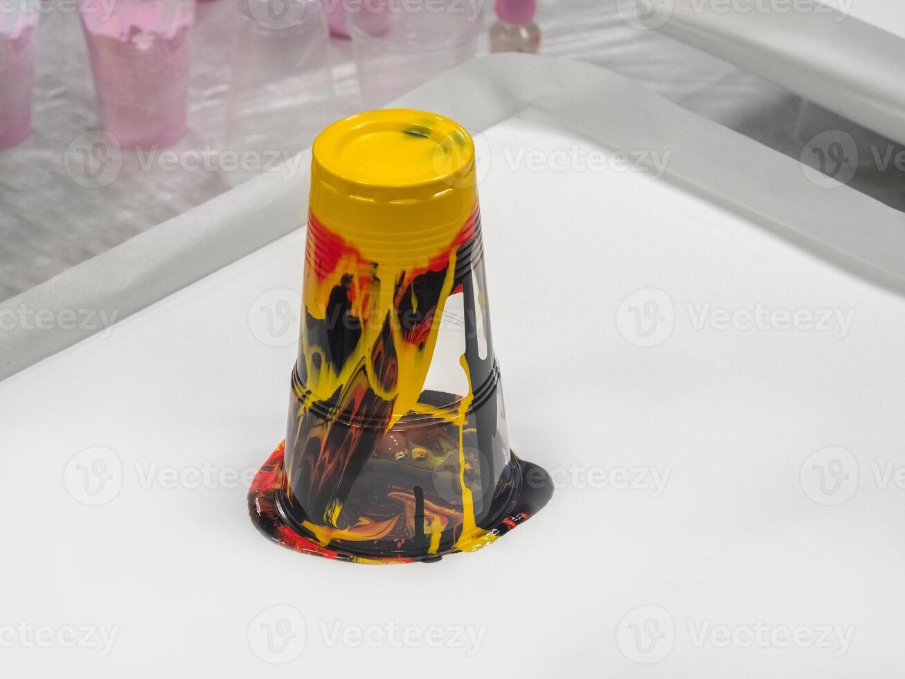 An inverted glass with leaking colored paint. Liquid acrylic creativity, preparatory work. photo