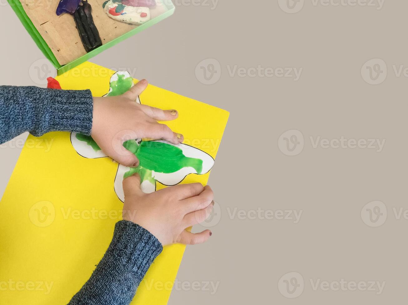 Top view children's hands sculpt a butterfly from plasticine. Child playing and creating butterfly from play dough. Homemade clay. Isolate, copy space. photo