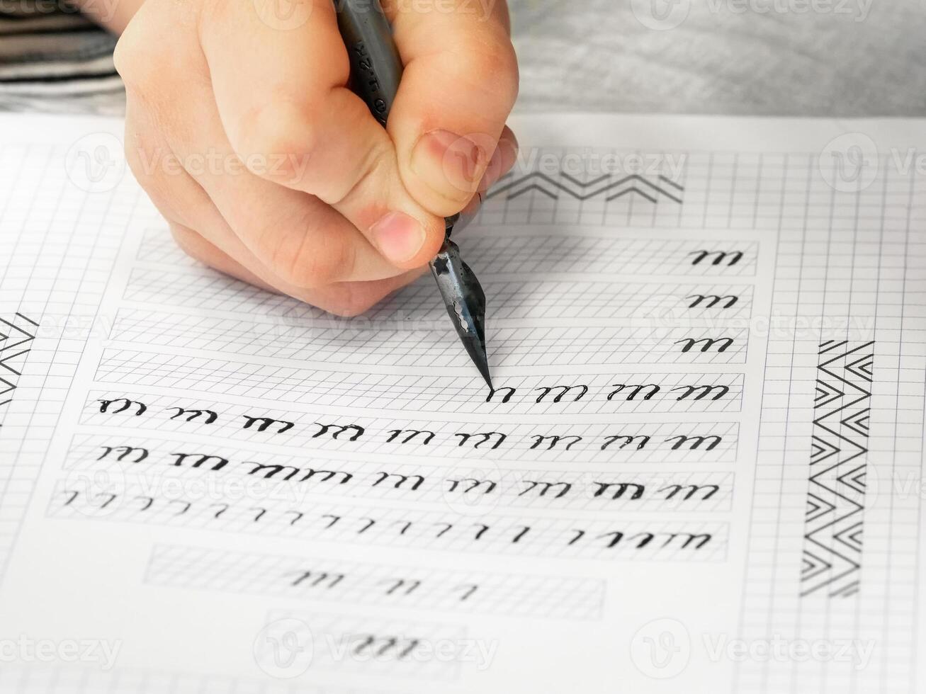 Close-up pupil's hands are writing calligraphy in a notebook. Schoolboy calligraphy performs a task at the workplace. Concept of children's education, teaching knowledge, skills and abilities. photo
