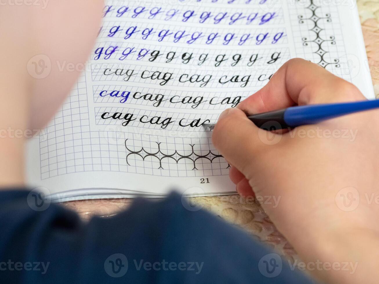 Writing homework. Close-up of girl hand with pen writing russian words by hand on traditional white notepad paper. The girl writes his first letter in Russian. photo