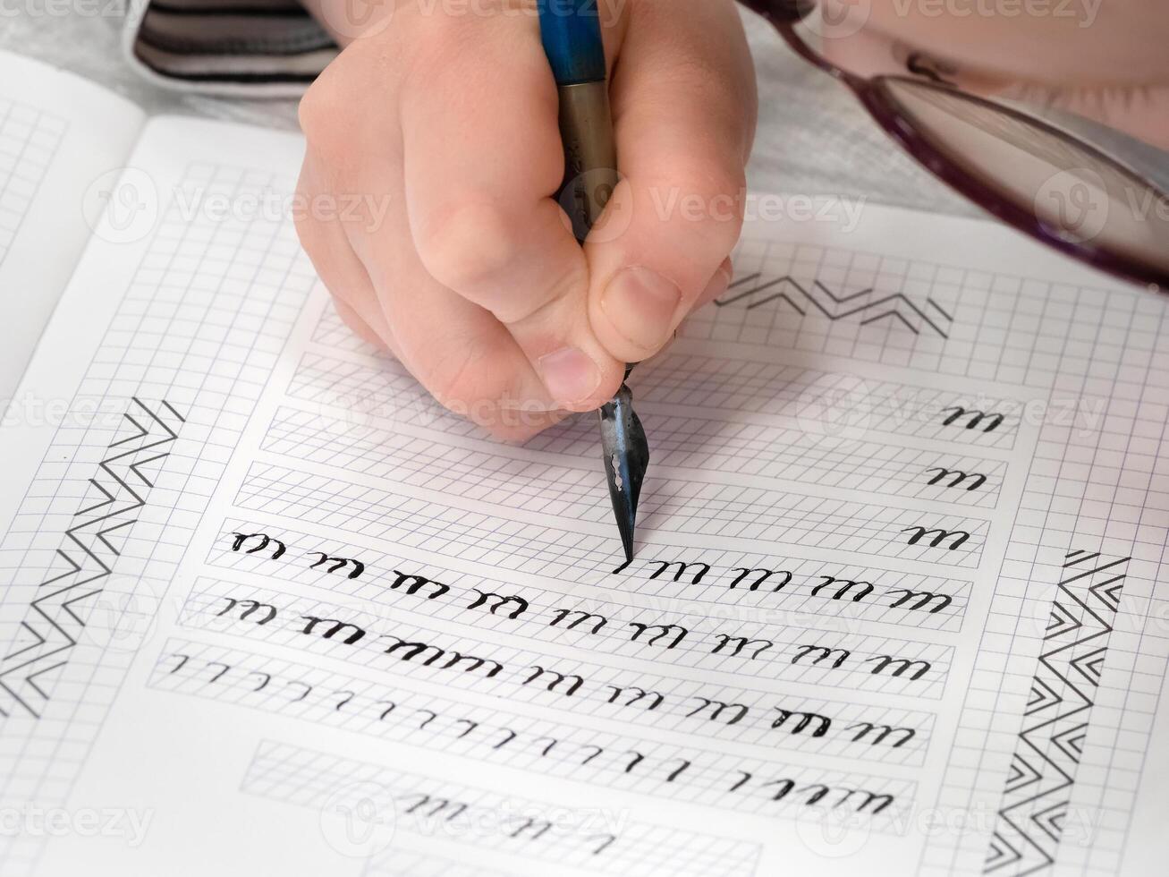 hands are writing calligraphy in a notebook. Schoolboy calligraphy performs a task at the workplace. Concept of children's education, teaching knowledge, skills and abilities. photo