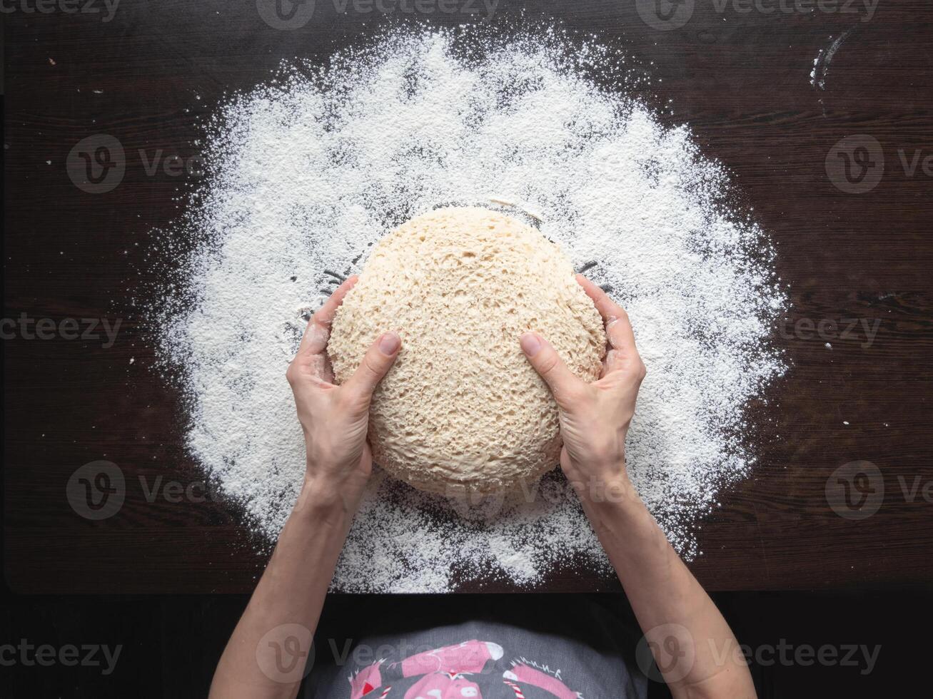 Baker's hand holds the raw yeast-free dough on a dark background. photo