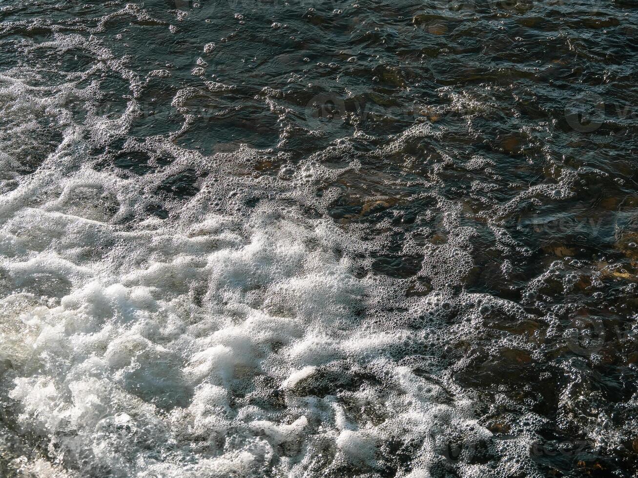 Flowing water texture. White water foam, small waterfall, water background. photo
