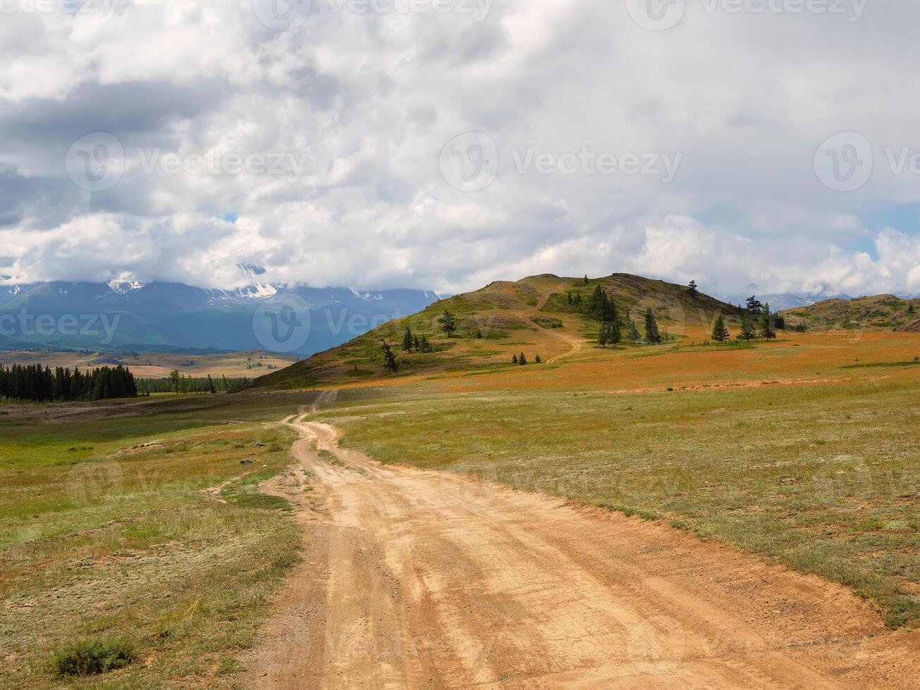 Way to the distance, way over the hill to the sky. Dirt road through the field. Field with a dirt road. photo