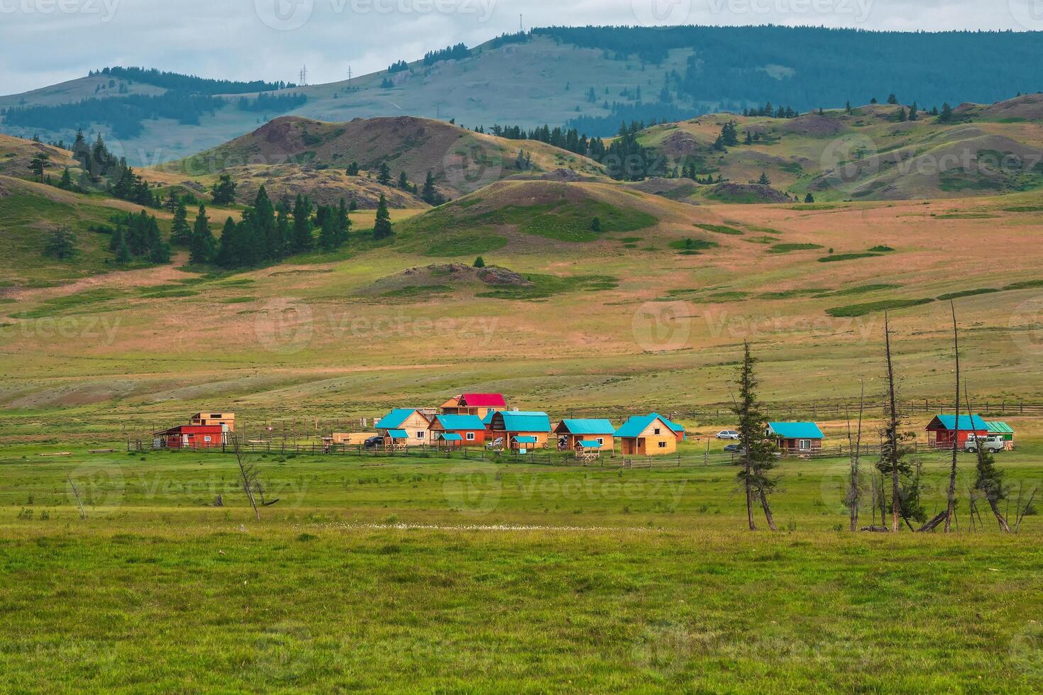 Modern countryside in highlands. Collective camping to the distance, tourist complex, wooden guest houses against the background of green hills. Farmstead in the steppe. photo