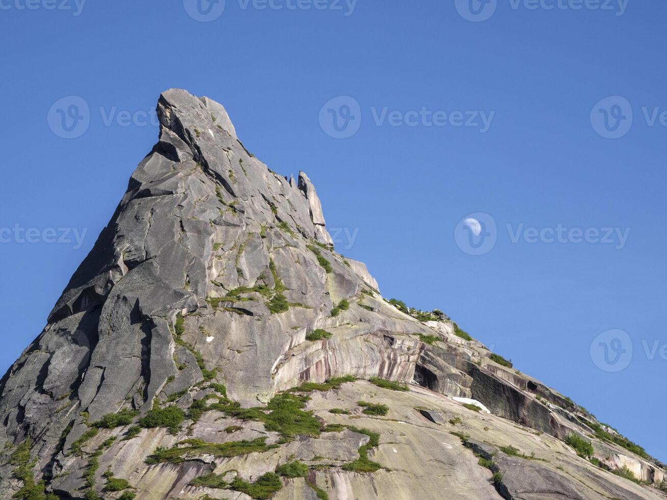 Moon over the sharp rock. photo