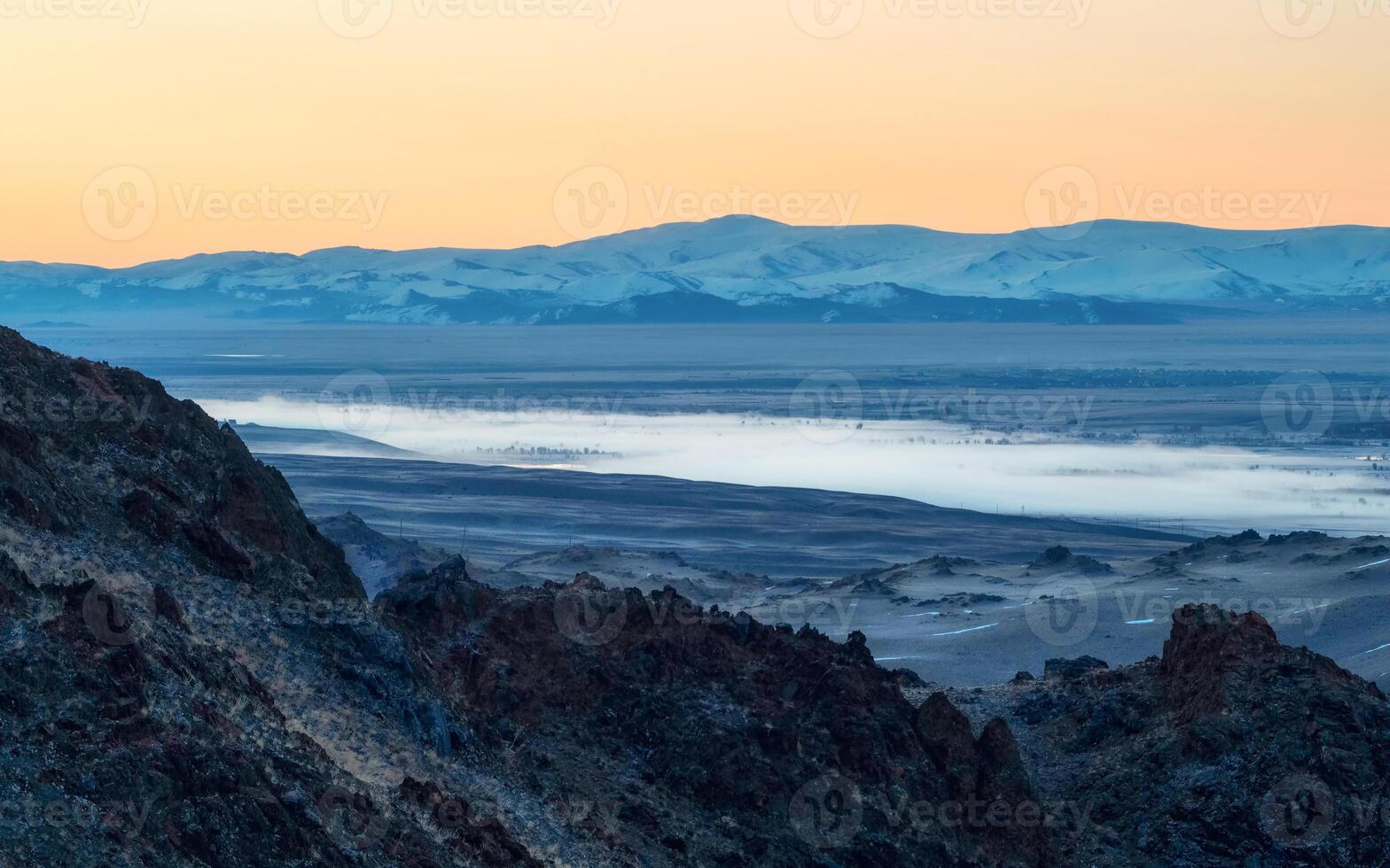 Valley with the river in the distance is covered with fog. photo