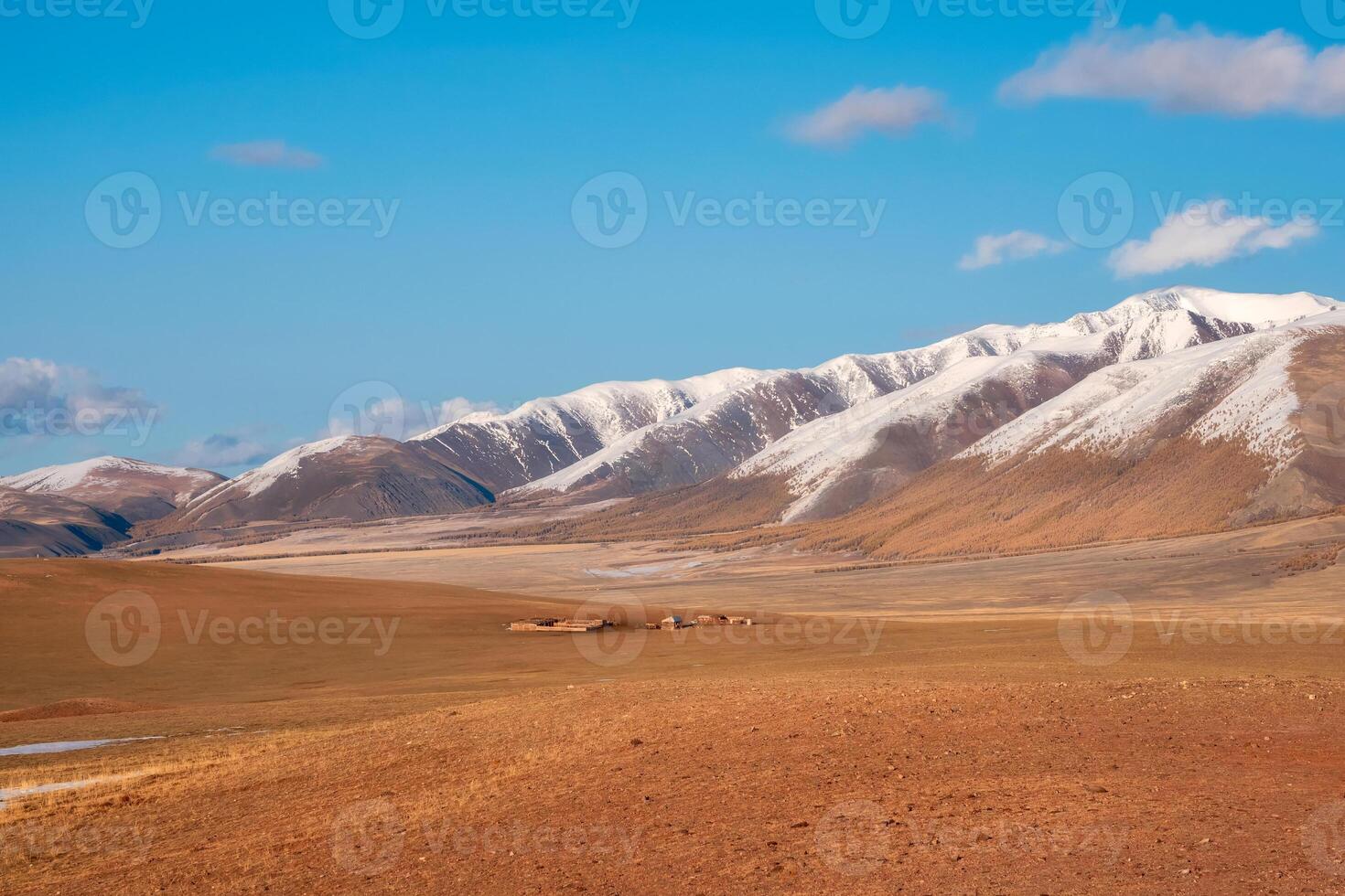 landscape of a wide prairie valley with a mountain range covered with snow photo