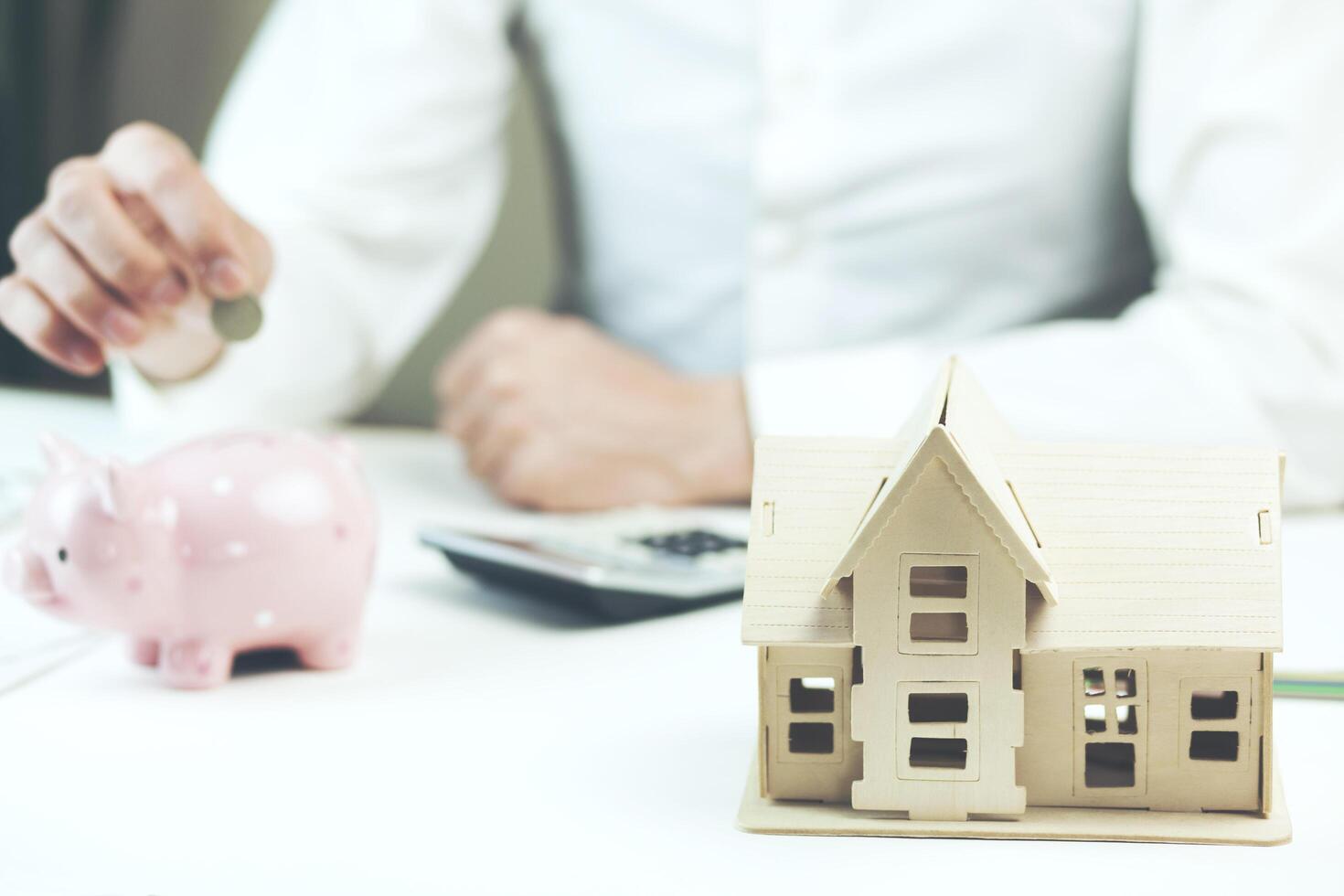 Man hand piggy bank with money and house model photo
