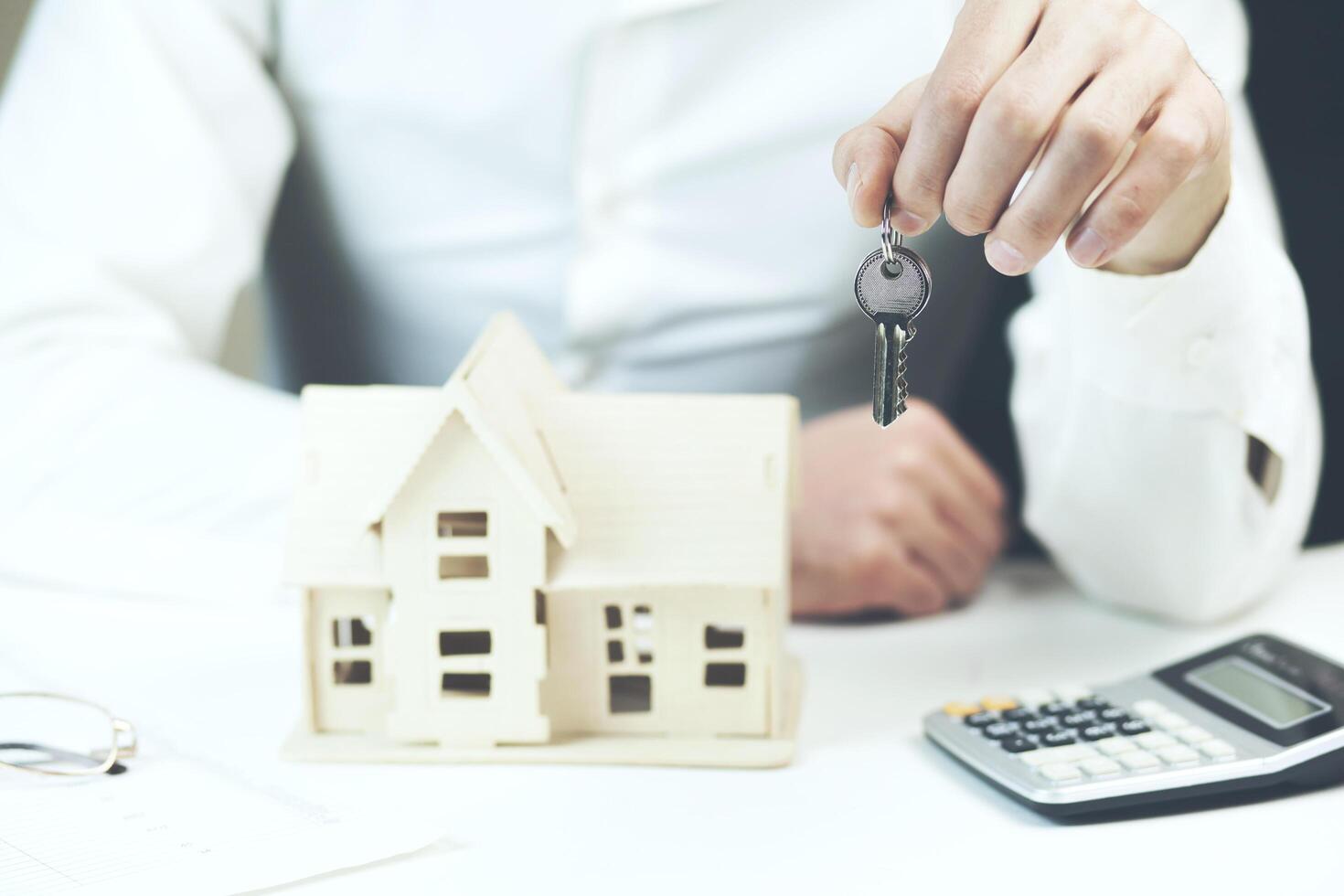 young man hand key with house model photo