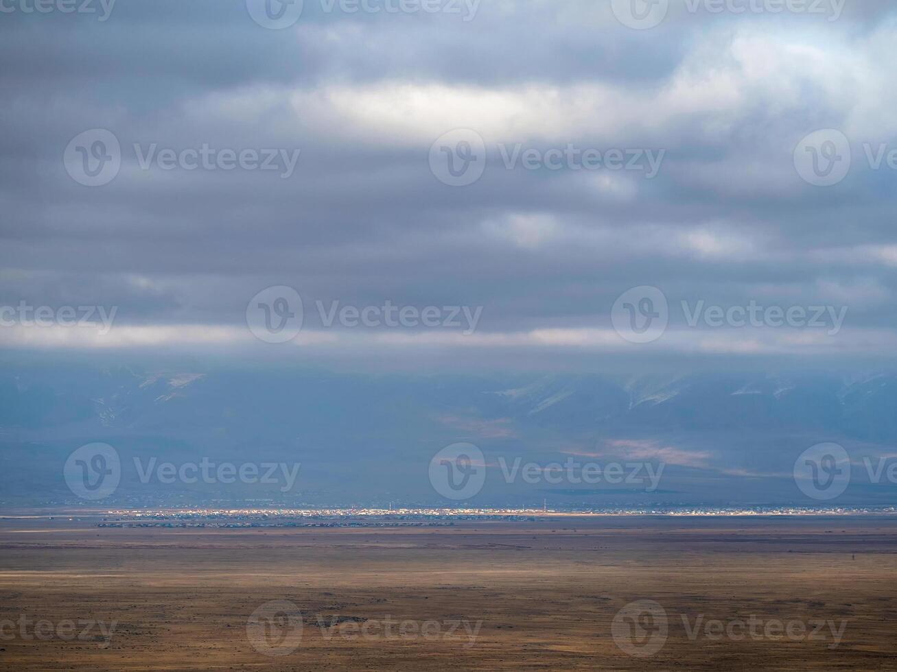 Thin line of a distant city in the steppe under a blue cloudy sky. Altai steppe. photo