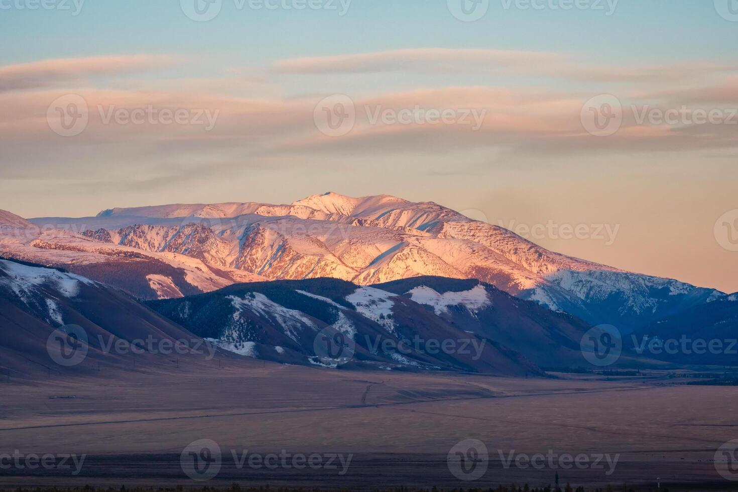 Sunrise or sunset sunlight on snowy mountains pink light morning or evening, Altai mountains on the background of the steppe, dawn in the mountains. photo
